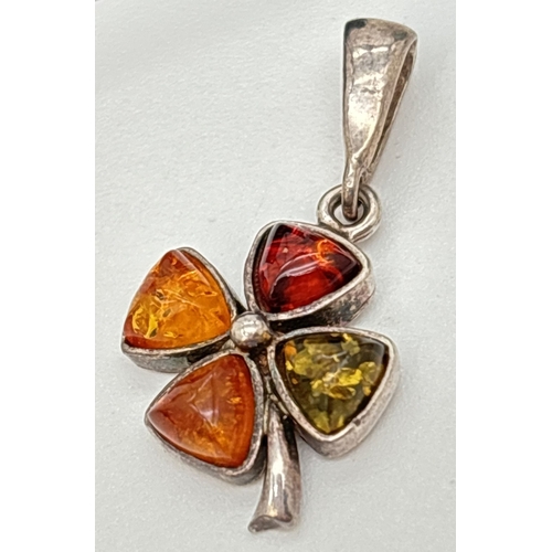 27 - An amber set silver four leaf clover pendant and matching drop style earrings. Each item set with gr... 