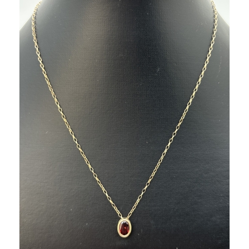 41 - A 9ct gold oval shaped bezel set garnet pendant, on a 16