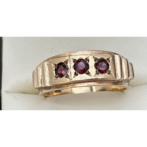 47 - A vintage 9ct gold band ring set with 3 round cut garnets and stepped detail to shoulders. Gold mark... 