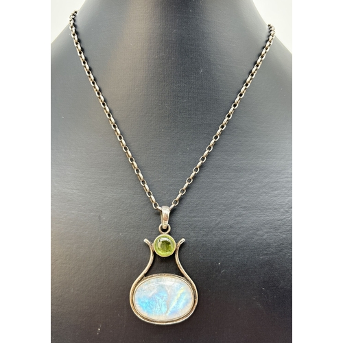 85 - A modern design large pendant set with a oval cabochon of moonstone and a round cut peridot. On a 16... 