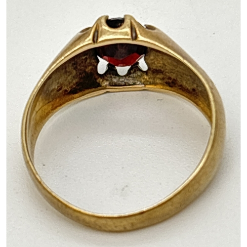 94 - A vintage 9ct gold men's signet ring set with an central oval cut garnet. Ridged design to shoulders... 