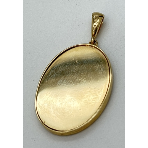  A 14ct gold oval shaped pendant with decorative mount containing a small print of the Madonna and ch... 