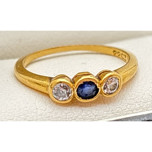 135 - A 22ct gold bezel set diamond and sapphire trilogy ring. Central round cut sapphire with a round cut... 