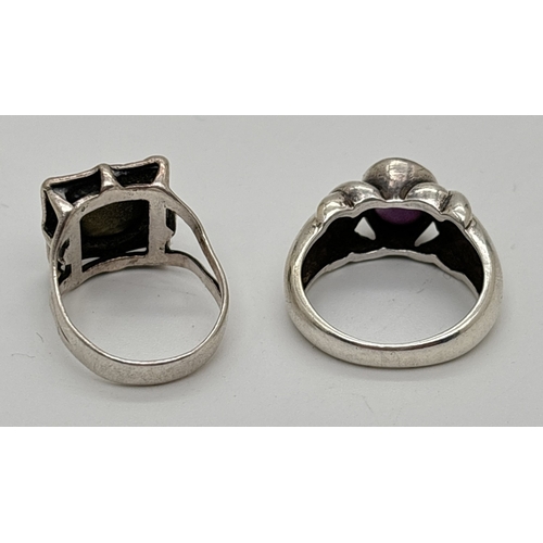 140 - 2 silver stone set rings. A bezel set amethyst cabochon with twist design to shoulders together with... 