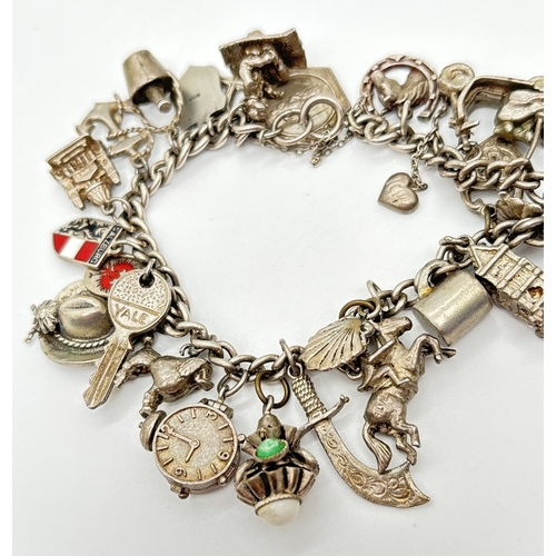  A vintage white metal charm bracelet with spring clasp, safety chain and 28 silver and white metal c... 