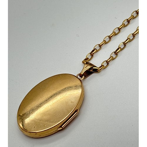 166 - A large oval 9ct gold locket with floral engraved decoration, on an 18