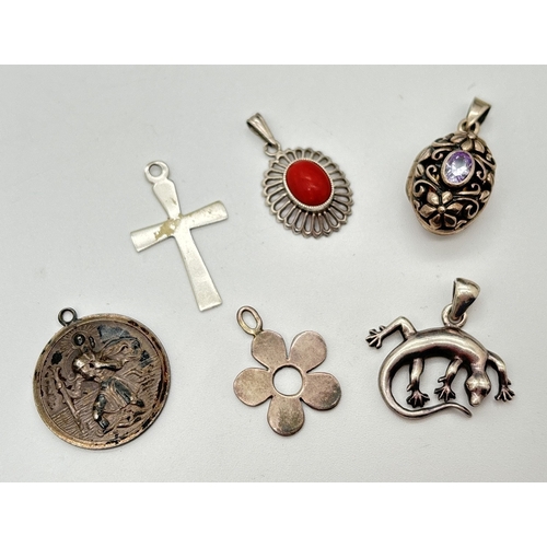 167 - 6 assorted silver pendants to include an oval stone set locket, a cross, a gecko, flower and St. Chr... 