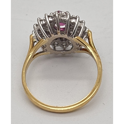 1001 - An 18ct yellow gold diamond and ruby cluster style ring. Central oval cut ruby surrounded by 22 roun... 