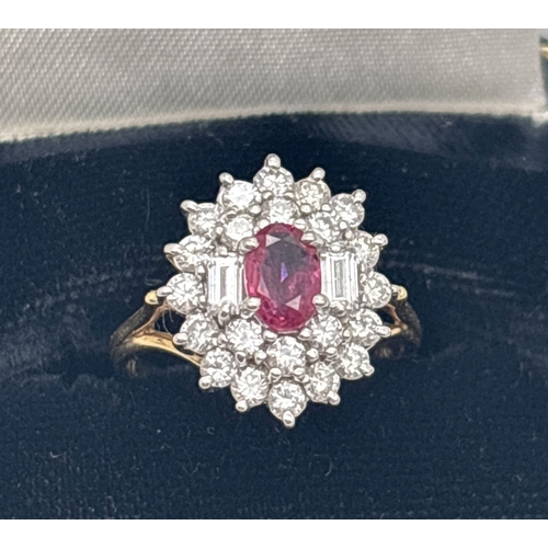 1001 - An 18ct yellow gold diamond and ruby cluster style ring. Central oval cut ruby surrounded by 22 roun... 