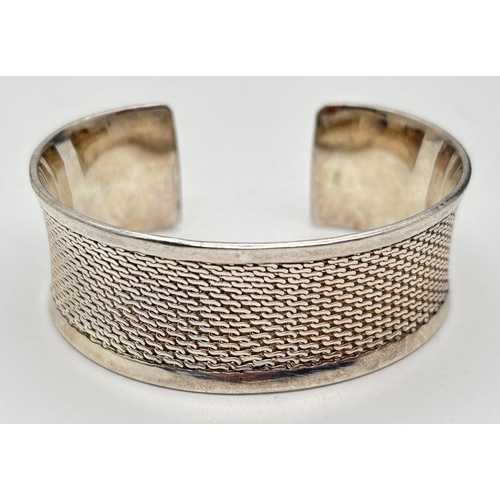 1006 - A 925 silver cuff bangle with S link decorated panel. Approx. 2.5cm wide. 925 stamped inside, Total ... 