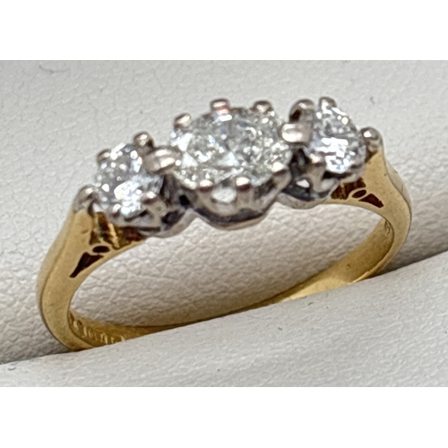 1018 - An 18ct gold and diamond trilogy style ring with central oval cut .50ct diamond and a round cut .15c... 