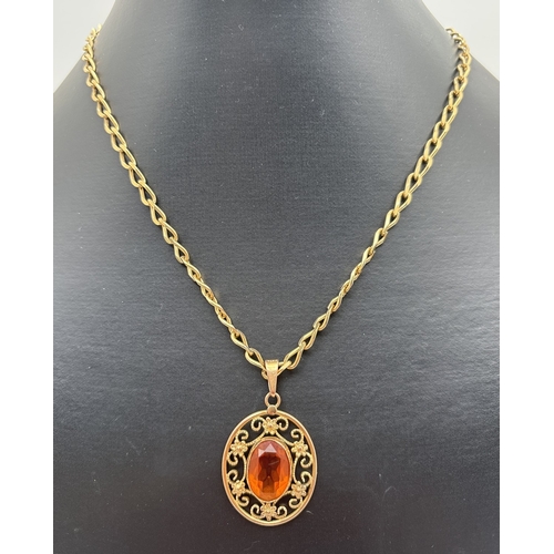 1028 - A vintage gold tone floral pierced work oval pendant set with a large orange stone by Sherman, Paris... 