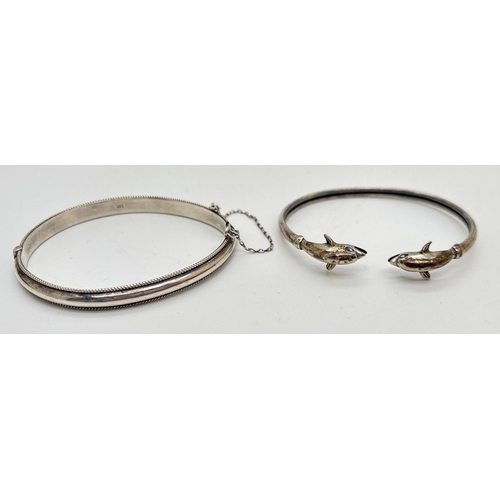 1034 - 2 x 925 silver bracelets. An open bangle with finials in the form of dolphins, together with a hinge... 