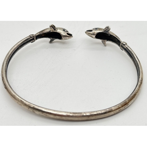 1034 - 2 x 925 silver bracelets. An open bangle with finials in the form of dolphins, together with a hinge... 