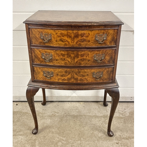 1377 - A small bow fronted walnut veneer 3 draw chest with decorative metal drop handles, raised on cabriol... 