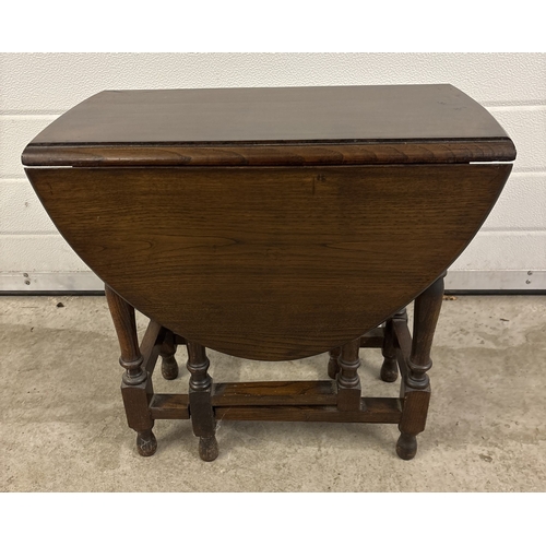 1378 - A small vintage dark oak, oval shaped drop leaf table with turned legs. Approx. 48cm tall.