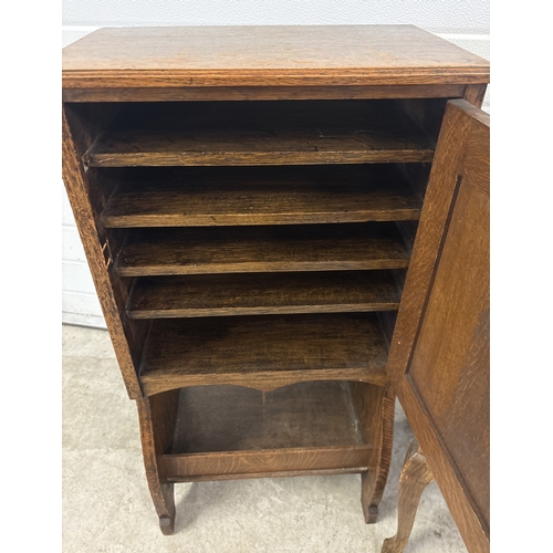 1383 - An early 20th century dark oak music cabinet together with a piano stool with green velvet upholster... 