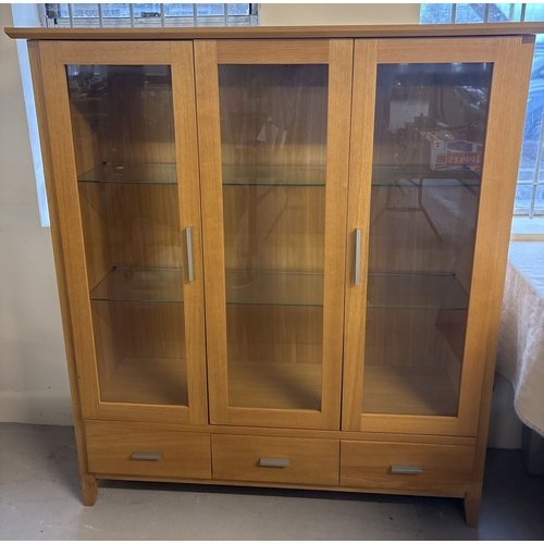 1384 - A modern light oak 2 door glass cabinet with fixed central glazed panel and 3 drawers. 2 glass shelv... 