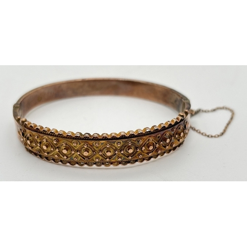 1089 - An antique gold bangle with fluted edge and diamond pattern detail. Push clasp with safety chain. Fu... 