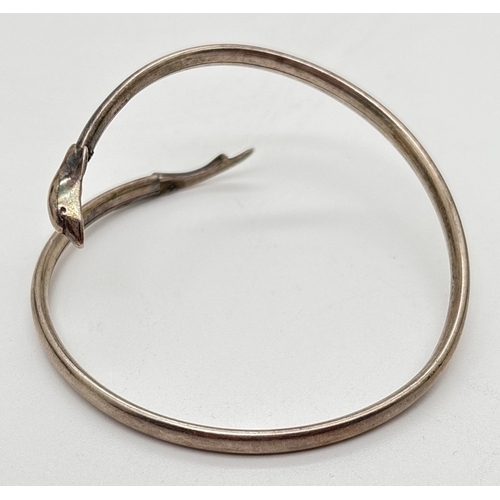 1101 - A small silver crossover style dolphin bangle with head and tail detail. Stamped silver inside bangl... 