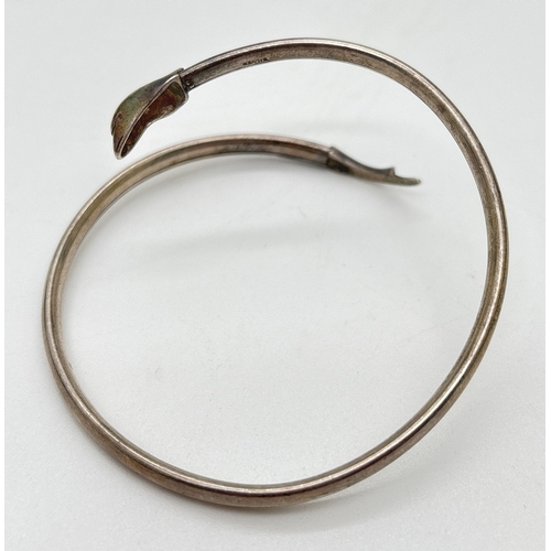 1101 - A small silver crossover style dolphin bangle with head and tail detail. Stamped silver inside bangl... 