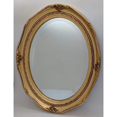 1403 - An oval gilt framed wall hanging mirror with floral decoration to frame. Frame approx. 48 x 38cm.