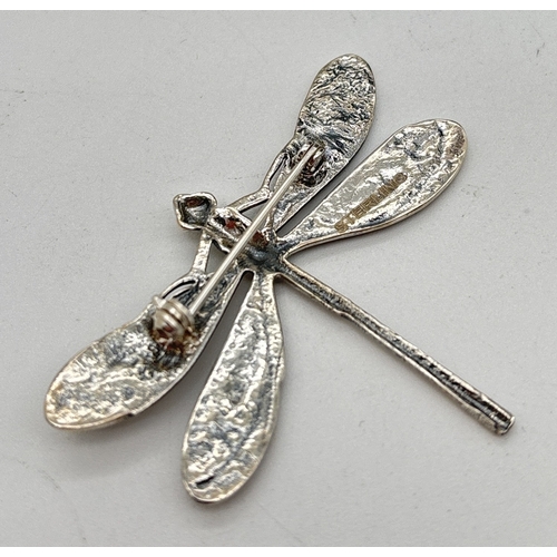 1103 - A silver brooch modelled as a dragon fly with embossed floral detail to wings. Reverse stamped sterl... 