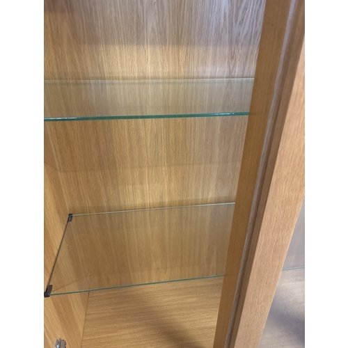 1384 - A modern light oak 2 door glass cabinet with fixed central glazed panel and 3 drawers. 2 glass shelv... 