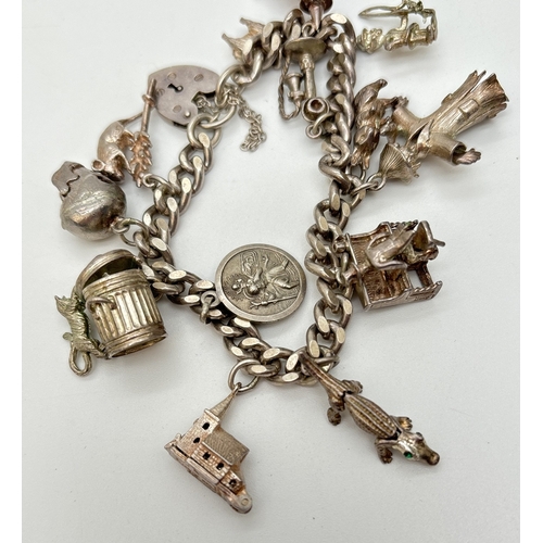 52 - A vintage silver charm bracelet with padlock, safety chain and 13 silver & white metal charms, some ... 