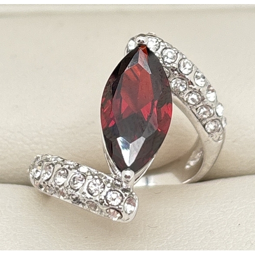 1064 - A rhodium plated twist design cocktail ring set with Swarovski crystals. Central marquise cut red st... 