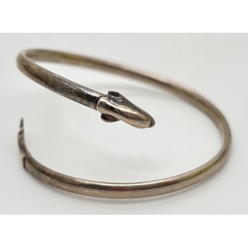 1101 - A small silver crossover style dolphin bangle with head and tail detail. Stamped silver inside bangl... 