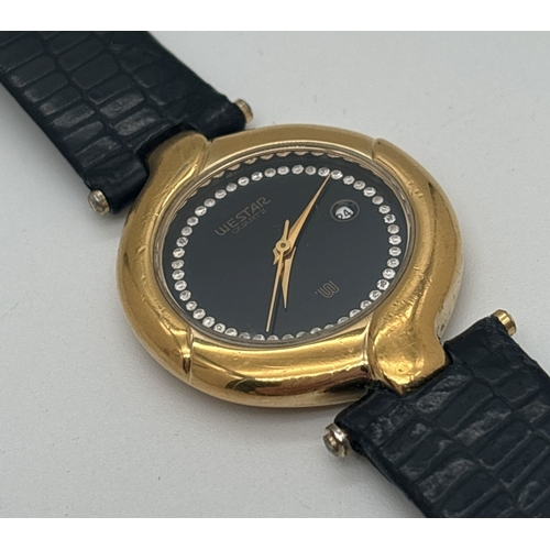 1157 - A ladies vintage wristwatch by Westar with black leather strap and 18ct gold plated twist design cas... 