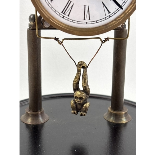 1212 - An unusual glass domed clock with swinging monkey pendulum. White enamelled face with roman numeral ... 