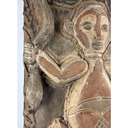 1258 - A very large carved tribal panel of an figure holding a snake, with lizard detail to bottom. Painted... 