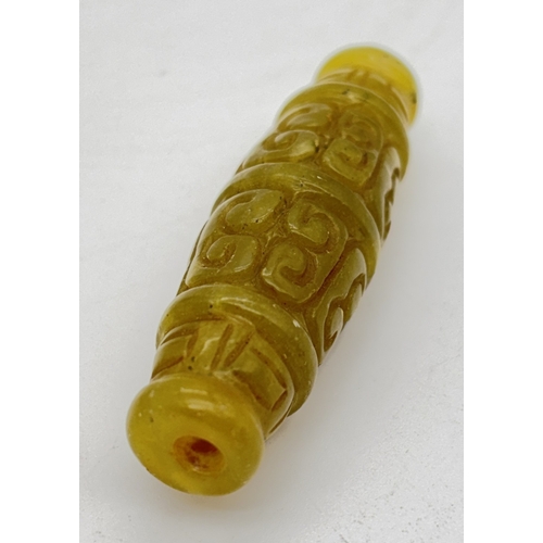 1265 - A green jade Tibetan dzi bead with carved design. Approx. 6.5cm long.