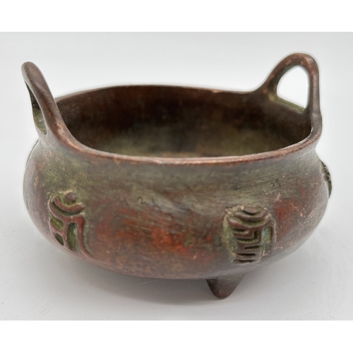 1266 - A small Chinese bronze 2 handled censor raised on tripod feet, with embossed characters to outer bow... 