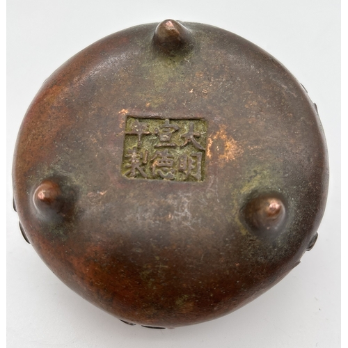 1266 - A small Chinese bronze 2 handled censor raised on tripod feet, with embossed characters to outer bow... 