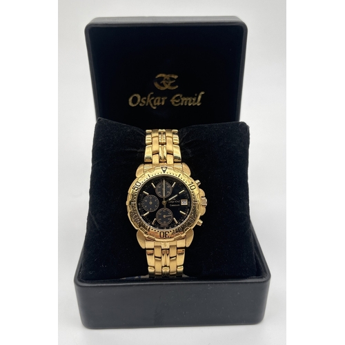 A boxed Oskar Emil Caesium chronograph wristwatch with gold plated case and strap. Black face and gold hour markers, hands and dials. Seconds hand and date function. Comes with 2 extra links and original guarantee card. In working order.