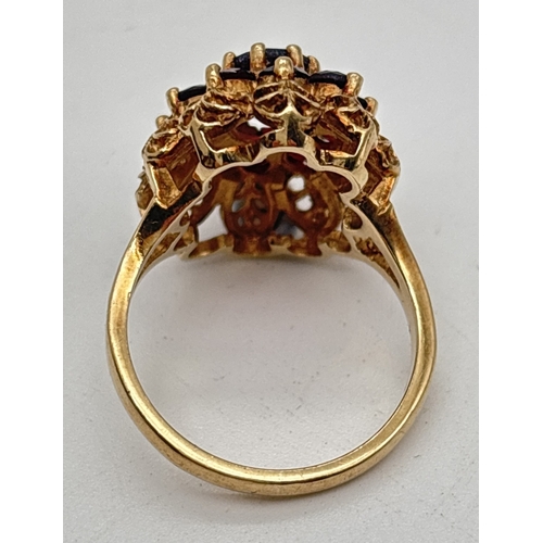 1107 - A vintage 9ct gold garnet set cluster style ring. High set filigree style mount with split shoulders... 