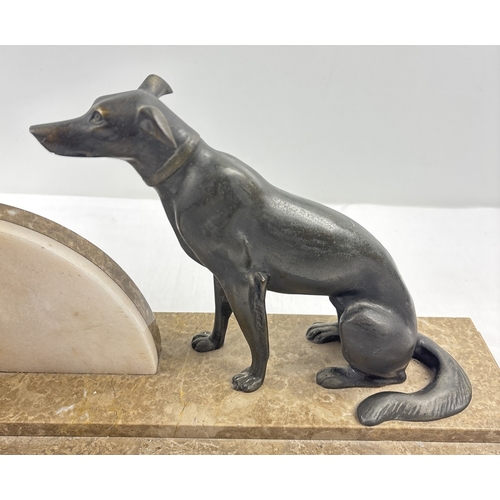 1367 - An Art Deco marble mantle clock of stylised design, mounted with spelter dog figurine. Modelled with... 