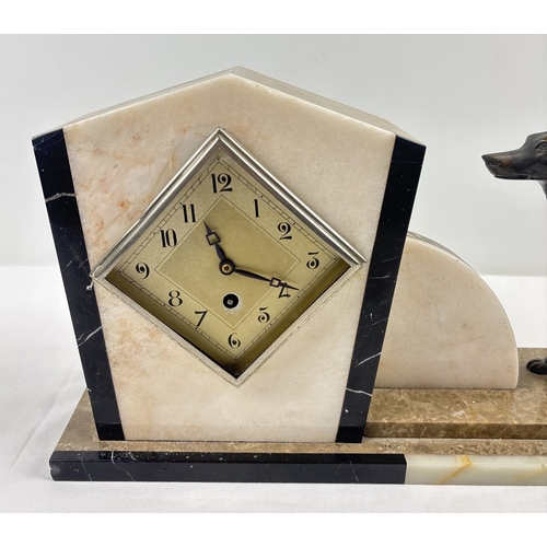 1367 - An Art Deco marble mantle clock of stylised design, mounted with spelter dog figurine. Modelled with... 