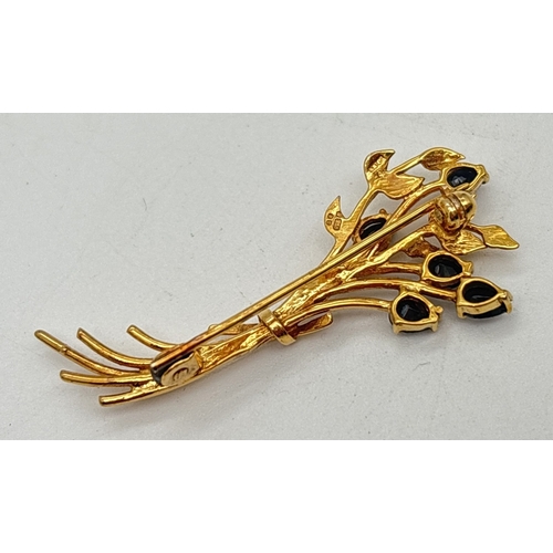 1003 - A 9ct gold floral spray brooch set with 5 pear cut blue sapphires. Gold marks to back of brooch and ... 