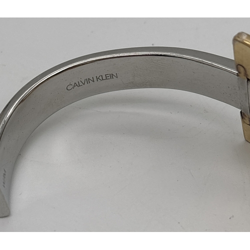 1017 - A modern design silver and gold tone cuff bangle by Calvin Klein. Designer name stamped inside.