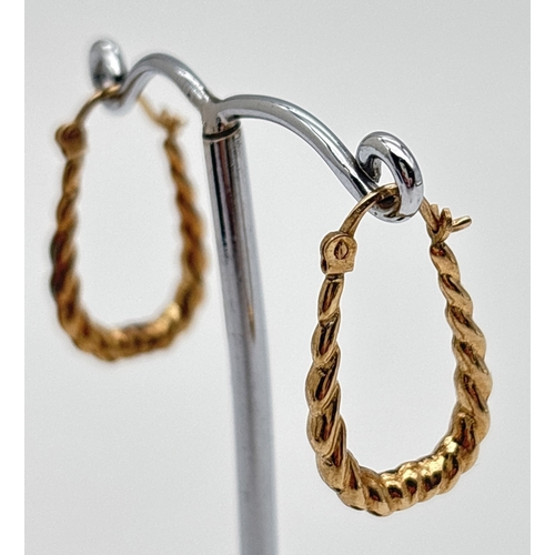 1021 - A pair of 9ct gold elongated twist design hoop earrings with hinged posts. Stamped 375 on posts. App... 