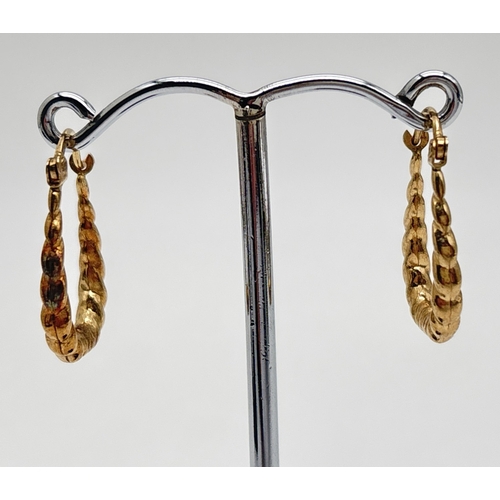 1021 - A pair of 9ct gold elongated twist design hoop earrings with hinged posts. Stamped 375 on posts. App... 