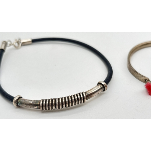 1033 - 2 silver bracelets. A modern design silicone bracelet with long silver barrel bead and spiral decora... 