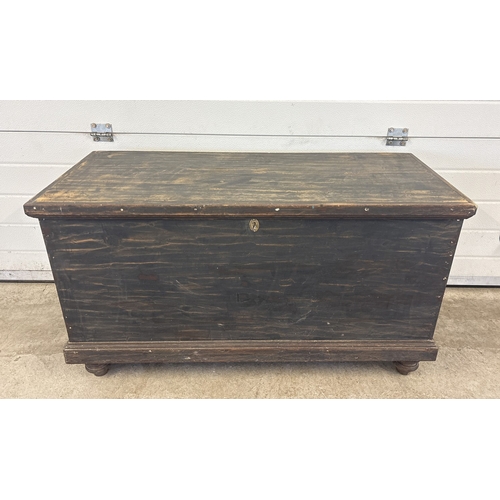 1432 - A large antique wooden chest/blanket box in a black rustic finish with lock and key. Black painted m... 