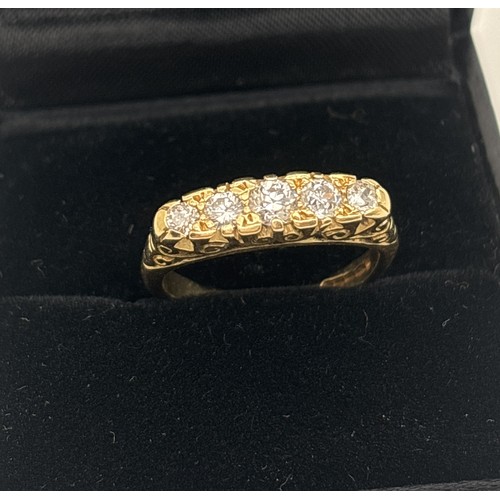 1002 - An Edwardian style 18ct gold ring set with 5 graduating sized diamonds. Pierced scroll work mount wi... 