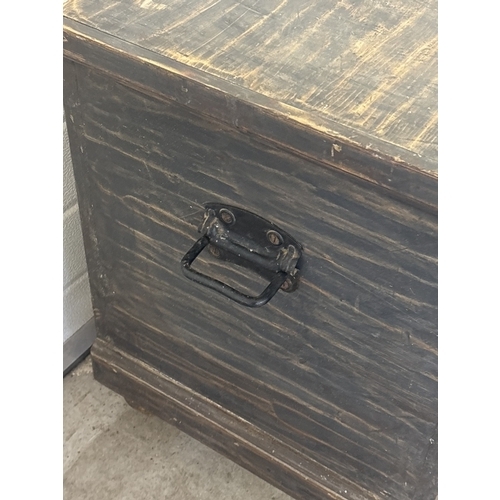 1432 - A large antique wooden chest/blanket box in a black rustic finish with lock and key. Black painted m... 