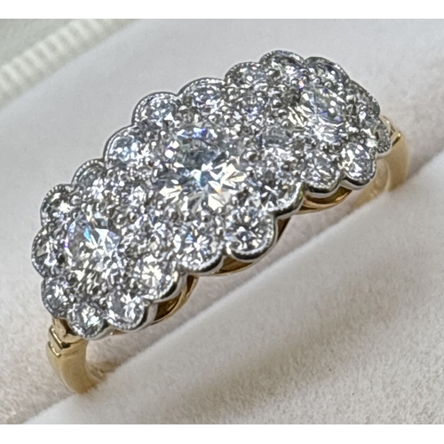 An 18ct gold & diamond triple cluster ring set with 27 brilliant cut diamonds. Mounted in platinum milgrain settings with 18ct yellow gold under bezel and shank. Total weight of diamonds approx 1.30ct. Size N. Total weight approx. 3.2g. Hallmarked inside band.